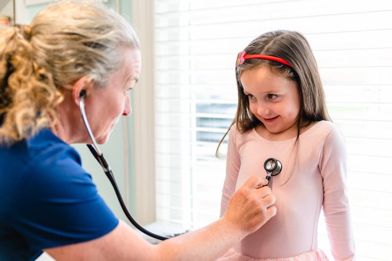 a provider listening to a young girls heart